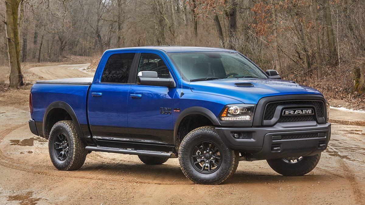 2018 Ram 1500 Rebel parked on dirt near a grove of trees.
