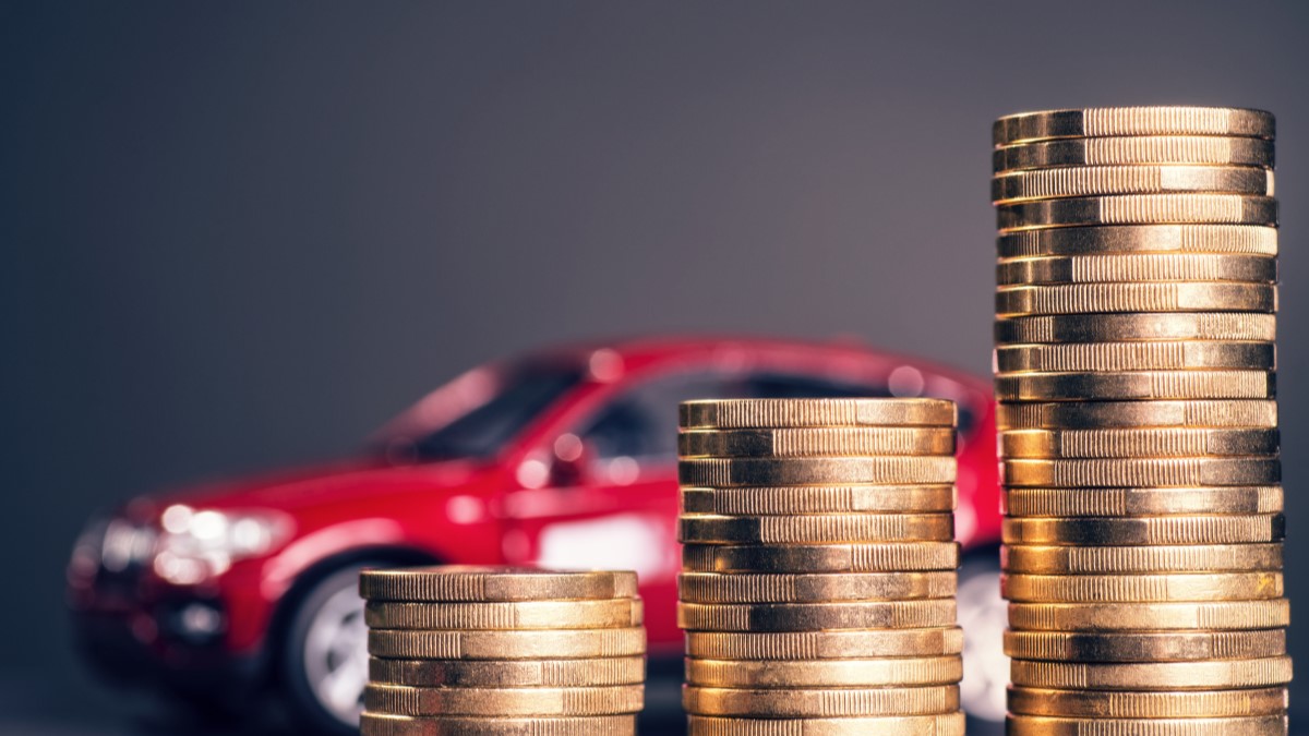 A toy car sits behind a pile of coins.