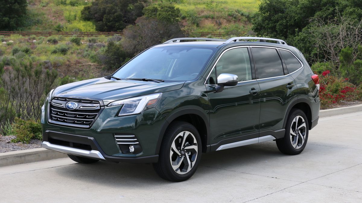 2024 Subaru Forester in green with shrubs and trees in the background.